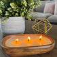 Lit wood bowl scented candle in a family room.  Luxury candle on a living room coffee table.