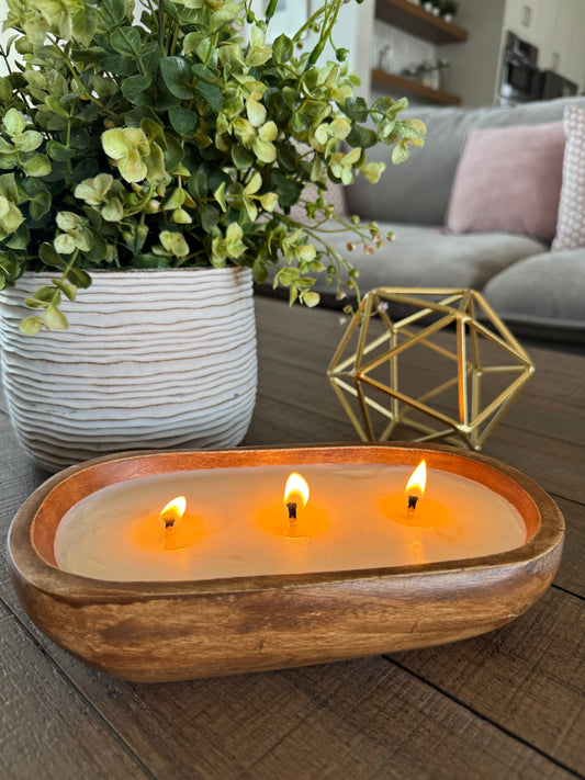 Lit wood bowl scented candle in a family room.  Luxury candle on a living room coffee table.