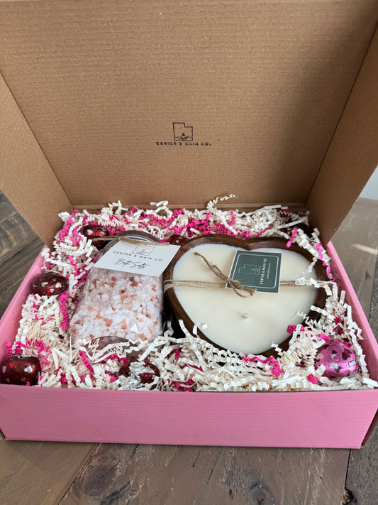 Top view of open Valentine's Gift box featuring Wooden Heart Bowl luxury candle with epsom bath salts and dove chocolates. 