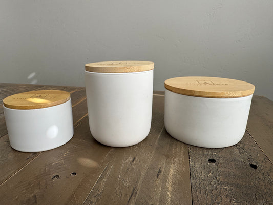 Three side view photos of white luxury candles with lids on a table. Scented candles on a table.